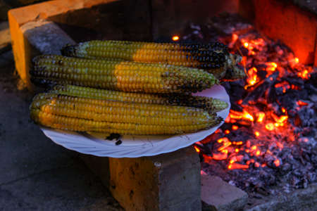 Slightly burnt corn at the ends. Roasted corn on a plate by the fire and grill where they are roasted. Zavidovici, Bosnia and Herzegovina.の写真素材