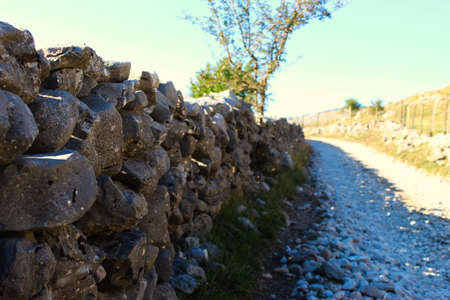 Large stones stacked in the wall to fence off the field from the road. Road to the old Bosnian...