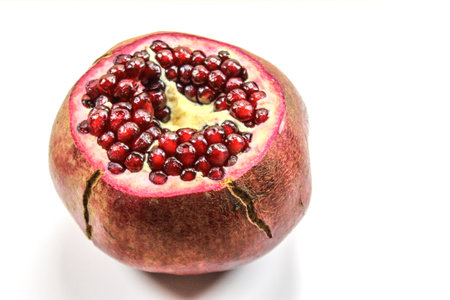 Pomegranate fruit seeds. A large red pomegranate isolated on a white background. Cut off the top of the pomegranate fruit. Whole pomegranate fruit with seeds.の写真素材