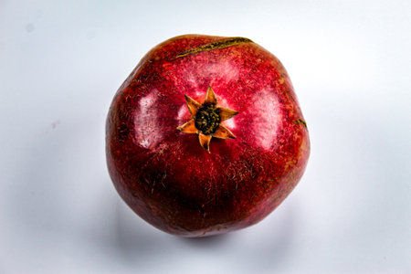 Red ripe pomegranate fruit against a white background. Anthers on ripe fruit up close. Rind outer skin of pomegranate. Macro of pomegranate fruit. Picture from top to bottom.の写真素材