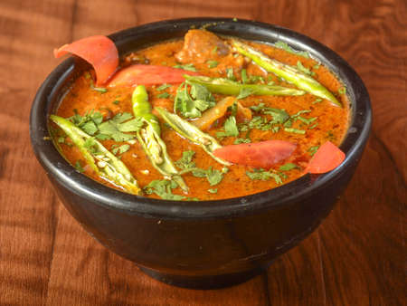 Mutton handi or Lamb curry, spicy and delicious dish served over a rustic wooden background,...