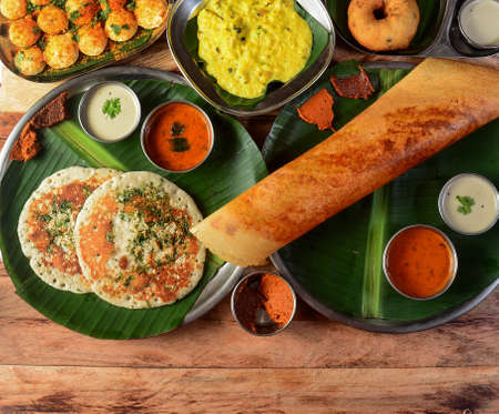 Assorted South indian breakfast foods on wooden background. Ghee dosa, uttappam,medhu...