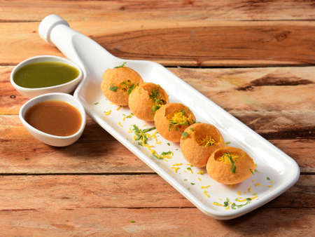 Pani puri is a famous midday snack in india, served over a rustic wooden background, selective focus