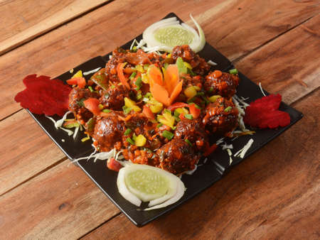 Veg Manchurian, Popular indo-chinese food made of cauliflower florets and other vegetable, served in...