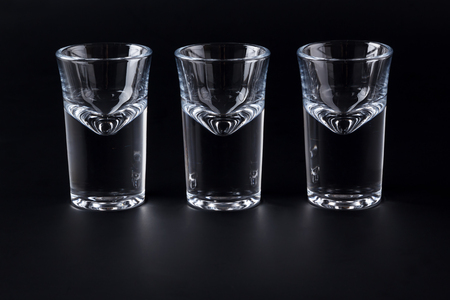 Three empty shot glasses on black backgroundの写真素材