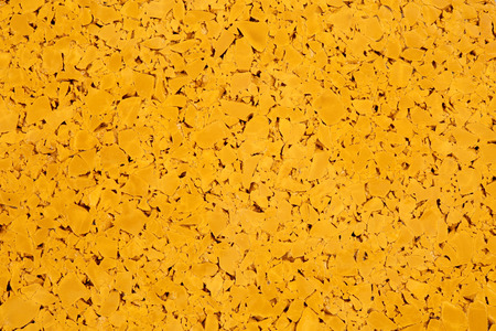 Dark yellow colored rubber floor background texture. Shock absorbent flooring for gyms, playgrounds, sports and running tracksの写真素材