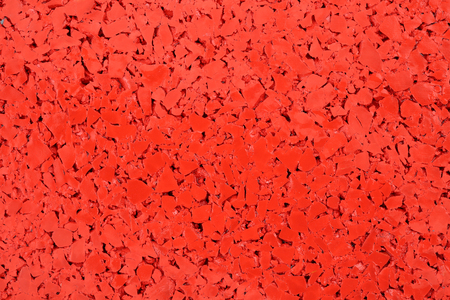 Red colored rubber floor background texture. Shock absorbent flooring for gyms, playgrounds, sports and running tracksの写真素材
