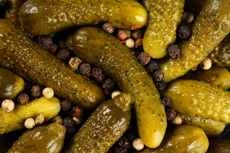 Top view, extreme close up of pickled gherkins (small cucumbers) sprinled with peppercorn mix. Macro food texture backgroundの写真素材