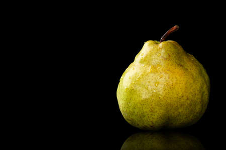 Fresh, organic, ripe, Green Anjou pear with the stem, water drops and reflection on a black backgroundの写真素材