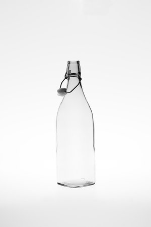 Monochromatic image of a retro empty square glass bottle with an open clip top stopperの写真素材