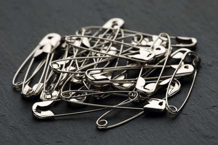 Extreme close up of a heap of safety pins on a black stone background