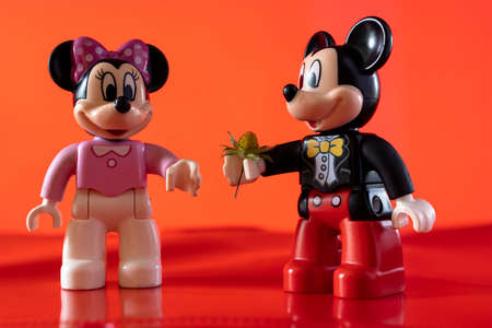 New York, USA - May 25, 2021: A close up shot of a miniature famous Disney character Minnie Mouse Disney character holding a flower against a pink background.のeditorial素材