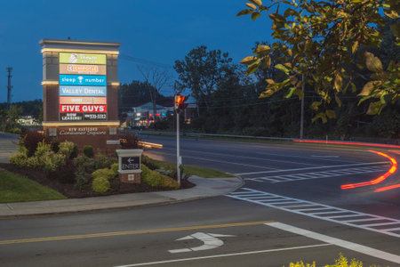 New Hartford, New York - Aug 18, 2019: Evening View of NY-5A and Plaza Sign with the Traffic Trails at New Hartford, New Yorkのeditorial素材