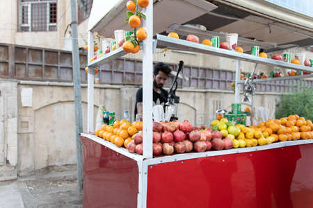 Baghdad, Iraq - October 4, 2021: Selective Focus View of Mobile Juice Seller with Pomegranate Stack in Focus and the Seller out of Focus.のeditorial素材