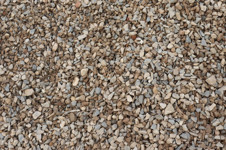 Background showing close up of natural small light brown and gray stones arranged randomly in a full frame seamless texture.の写真素材