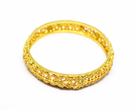 Detailed shot showcasing an exquisite golden bangle featuring elaborate ornamentation and a rich, lustrous tone against a white setting.の写真素材