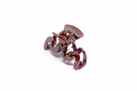 Close-up shot presents an iridescent metal hair claw clip featuring a spring and rounded edges against a clean, bright white backdrop, highlighting its unique colors.の写真素材