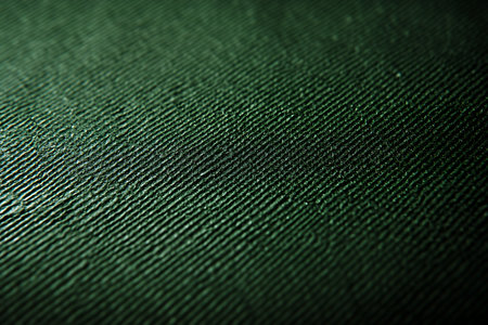 A macro shot reveals a textured surface with diagonal lines in varying shades of dark green. The texture fades into shadow towards the bottom right corner.の素材
