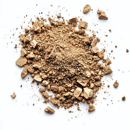 A textured heap of crumbled brown powder pieces and dust lies scattered on a bright white surface, captured in a detailed, close-up shot.の素材