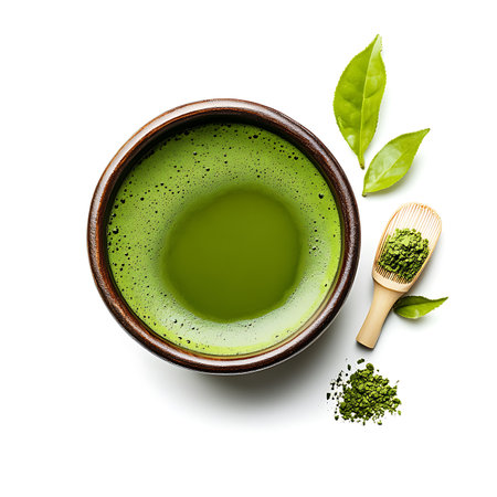 Overhead shot showcases matcha tea in a bowl with a wooden scoop, green tea leaves, and scattered powder against a clean, bright white backdrop.の素材