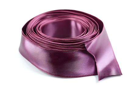Close-up shows rolled plum colored satin ribbon against a white backdrop. The focus is on the textures and depth of the wound ribbon.の素材