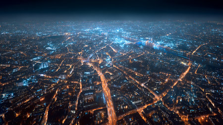 A high-angle view of a large city at nighttime, lit by thousands of lights and a river running through its center. The horizon is a dark, hazy, blueish hue.の素材
