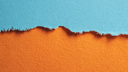 Macro photograph showcasing textured orange and blue paper meeting at a ragged tear. Captures the rough edges and detailed surface fibers. Use for backgrounds, crafts, or artistic projects.の素材