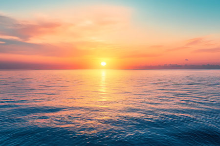 Gorgeous ocean sunset with serene water reflecting the colorful orange and pink sky. The sun glows brightly at the horizon, casting a warm glow over the tranquil sea.の素材