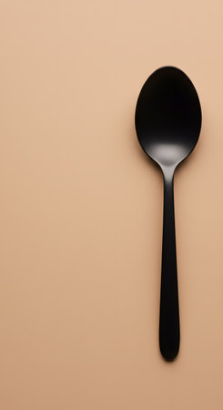 Black plastic spoon on beige background.の素材