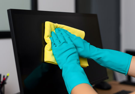 Hands in rubber gloves cleaning computer monitor with microfiber clothの素材