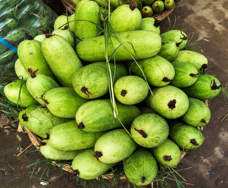 A close-up overhead view of a woven basket overflowing with vibrant, fresh green guavas, showcasing their textured skin.の写真素材