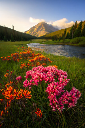 A picturesque landscape featuring a winding river, lush green hills, and a field of colorful wildflowers in full bloom.の素材