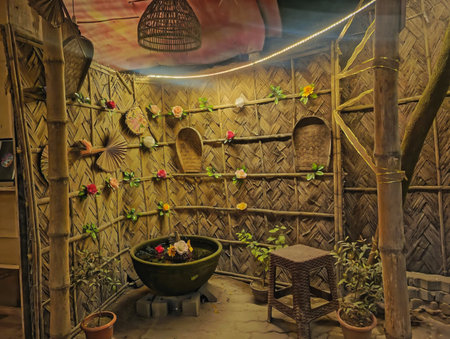 A dimly lit, rustic interior of a hut or dwelling, featuring bamboo walls, shelves filled with items, and a bowl of fruit.の素材