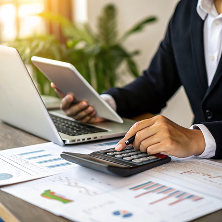 Business professional working on finances with laptop tablet and calculatorの素材