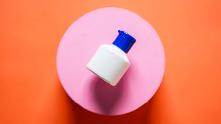 Cosmetic bottle on pink and orange background. Top view with copy spaceの素材