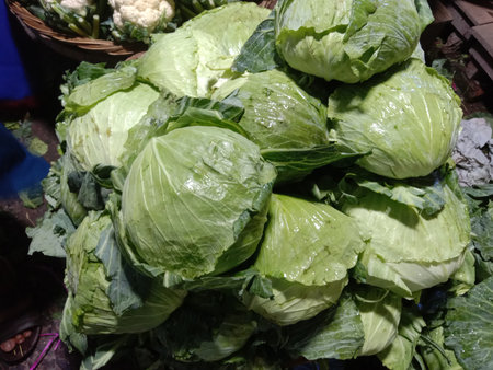 This image captures a vibrant display of fresh cabbages at a market. The cabbages are neatly...