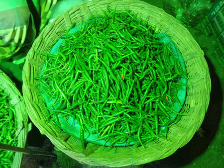A close-up image of fresh green leaves neatly arranged in a woven basket. The vibrant green color of the leaves indicates their freshness and quality. The basket appears to be handmade, adding a rustic touch to the overall presentation. The leaves are uniformly cut, suggesting they are ready for processing.の写真素材