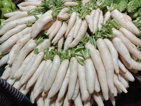 This image showcases a vibrant display of fresh white radishes at a market. The radishes are neatly...