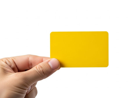 Hand holding yellow card isolated on white backgroundの素材