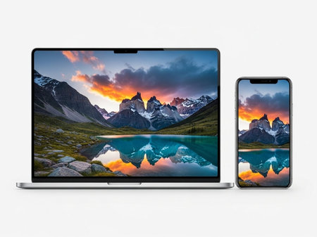 Laptop and phone displaying mountain landscapeの素材