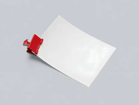 Blank white card held by a bright red binder clip on a light gray surfaceの素材