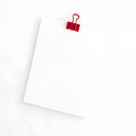 Clean white paper stack held together by a bright red binder clip on a white backgroundの素材
