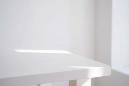 Clean white kitchen cabinets with soft light casting shadows on the surface.の素材