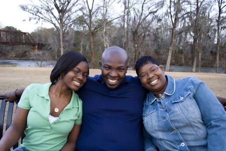 African american family sitting on a bench in a parkの写真素材
