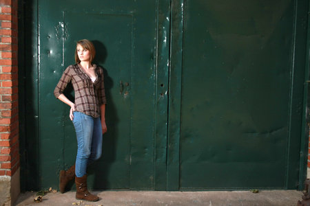 A young woman standing by s apir of green doorsの写真素材
