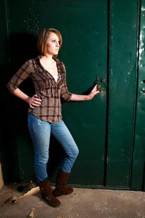 A beautiful young woman standing by a green doorの写真素材