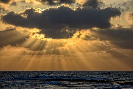 Beautiful cloudy sunset with sun beams over the sea
