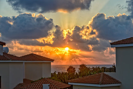 Sunset with sunbeams over luxurious holiday beach villas for rent on Cyprus coastの写真素材