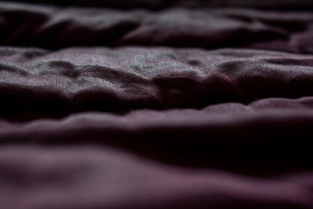 Shiny fabric texture with shadows. Abstract burgundy wallpaper.