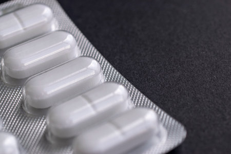 Part of a plate with pills on a black background close-up and place for text
